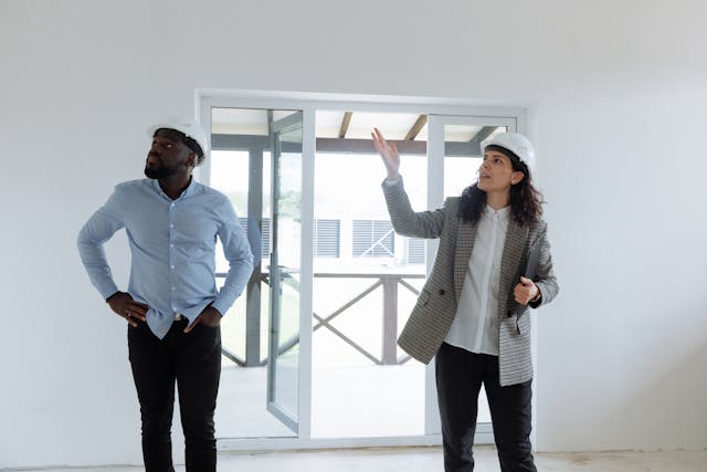 two people in hard hats looking at house